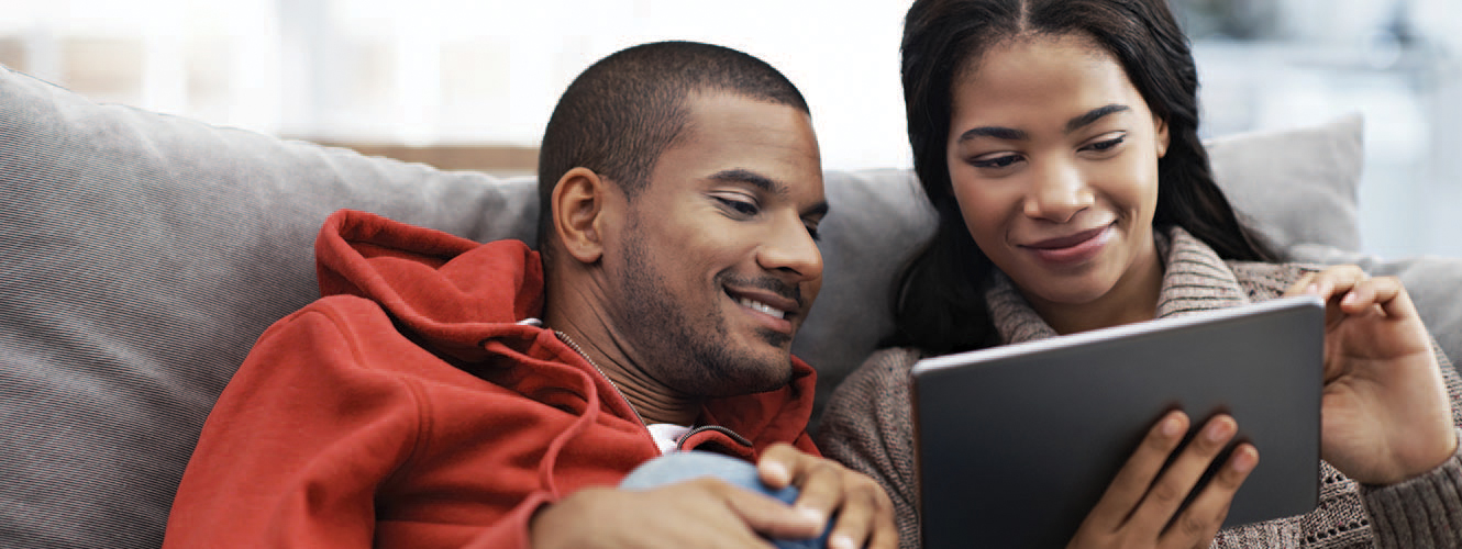 Couple sitting on the couch together looking at a tablet