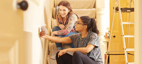 Two women sitting on the stairs looking at paint samples